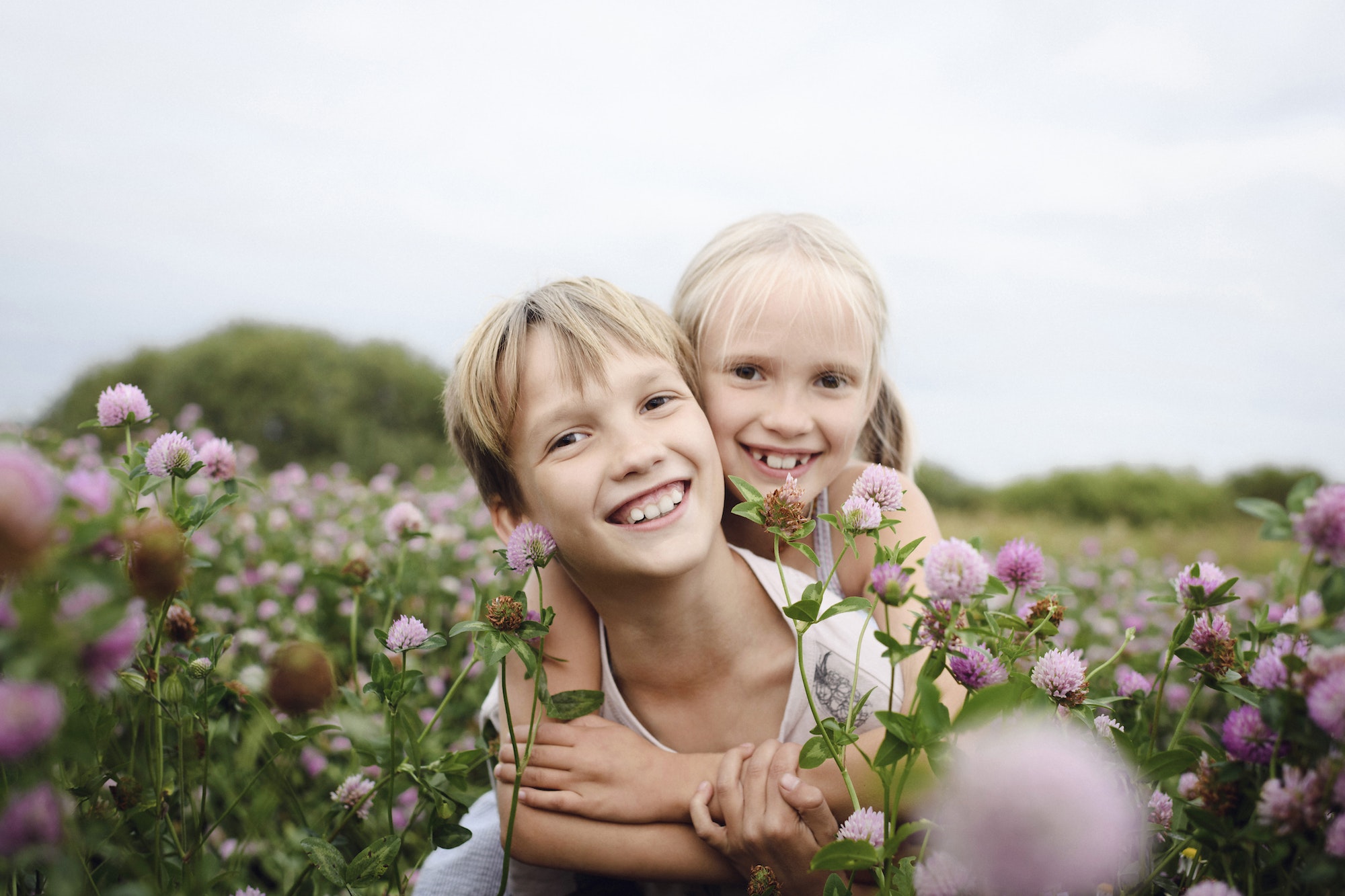 Two smiling children on clover field